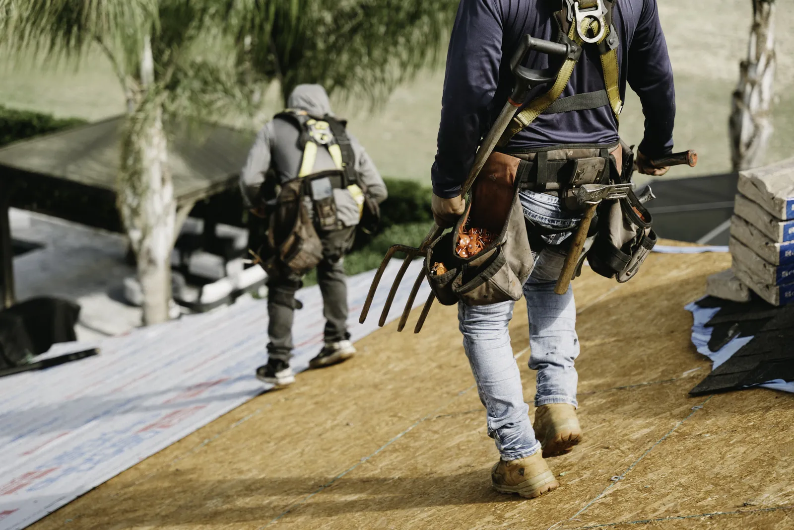 Roofing crew carrying tools onto a residential jobsite