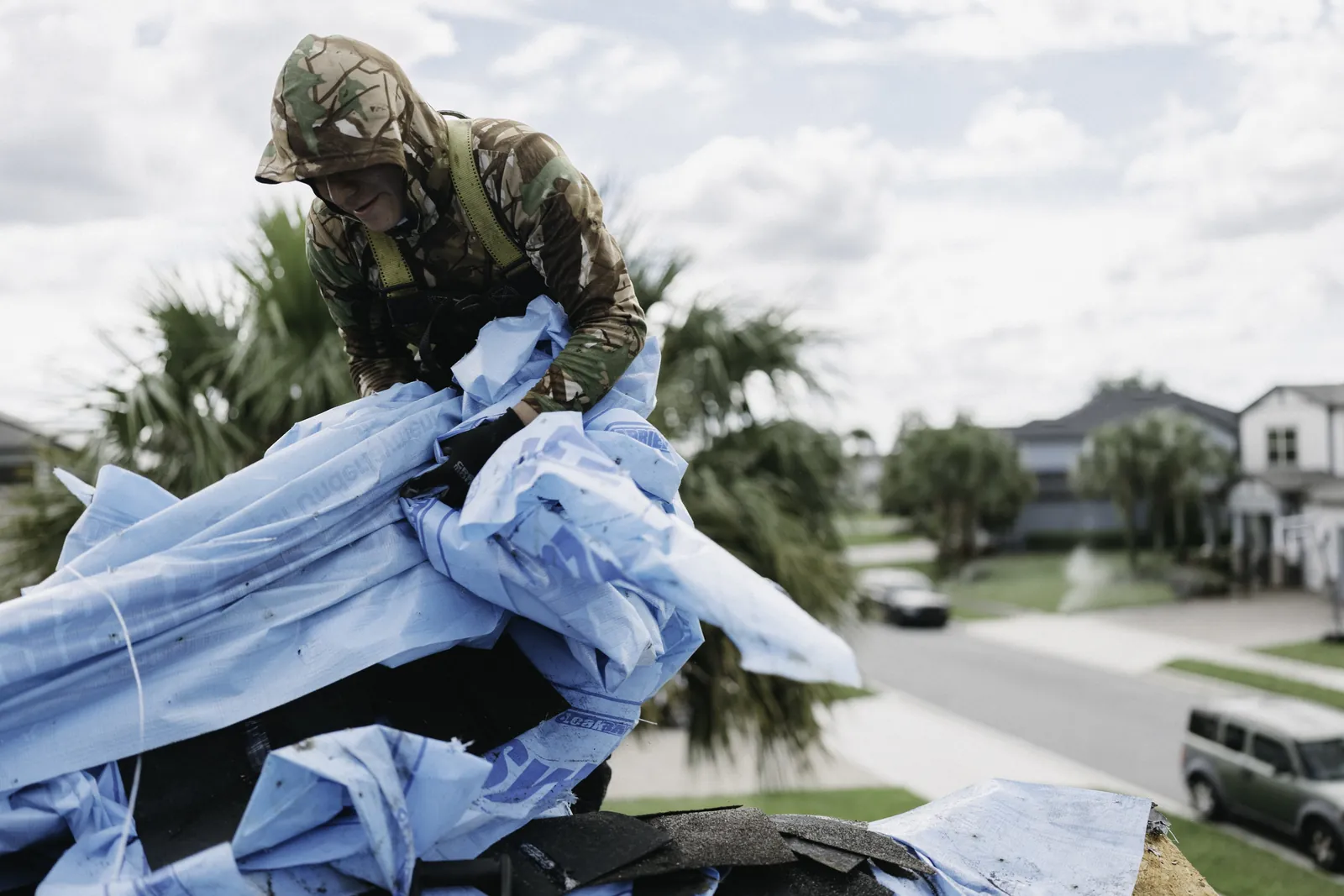 Roofing crew handling a protective tarp at a jobsite