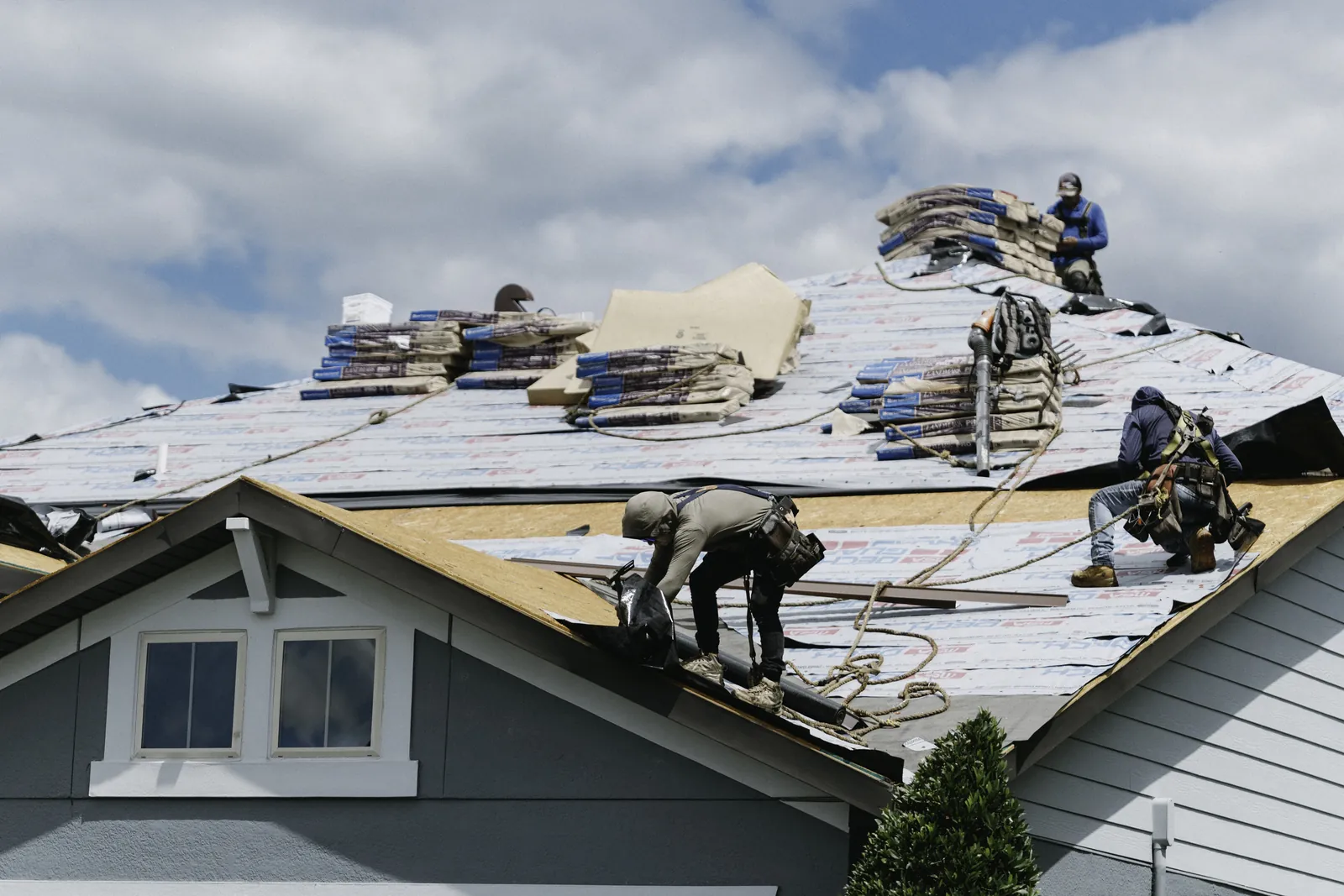 Roofing crew installing shingles across a residential roof