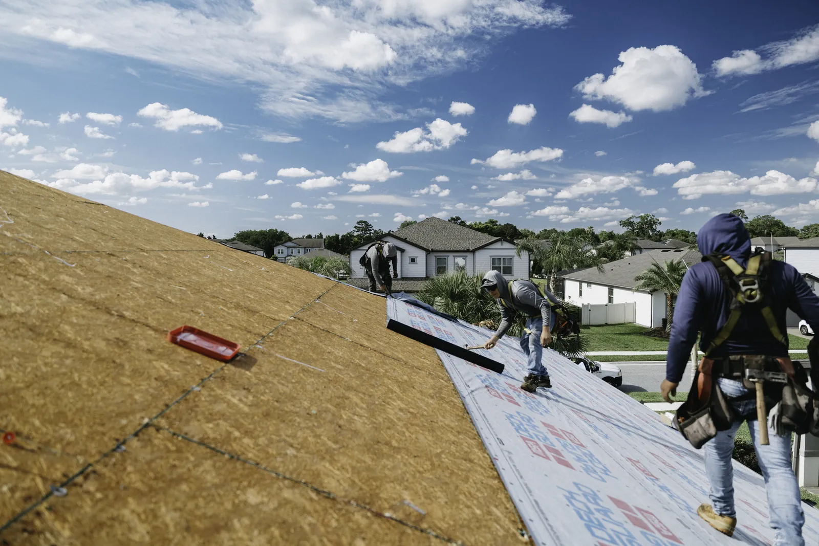 Roofing crew installing protective underlayment on a broad roof surface