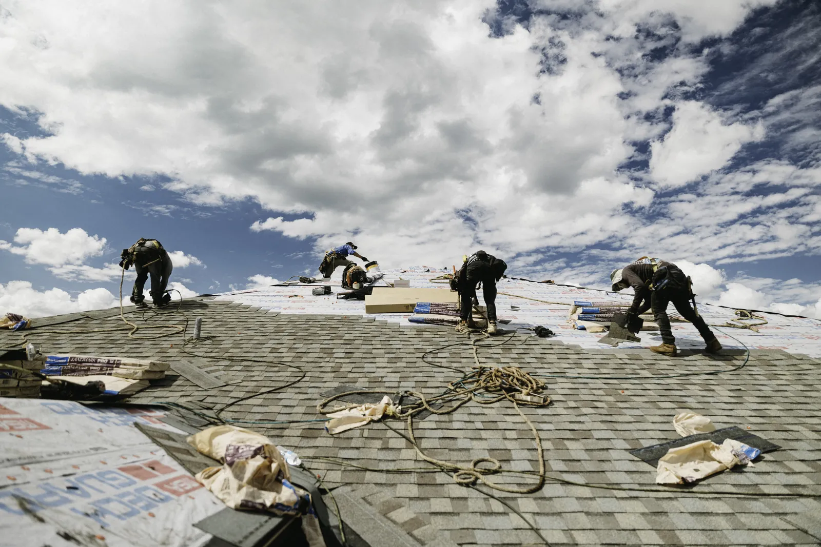 Roofing crew working across a broad low-slope roof