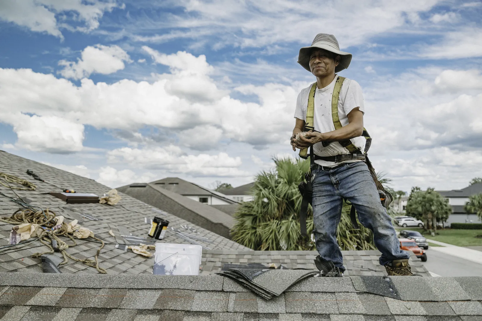 Roofer holding a cut shingle while inspecting a roof section