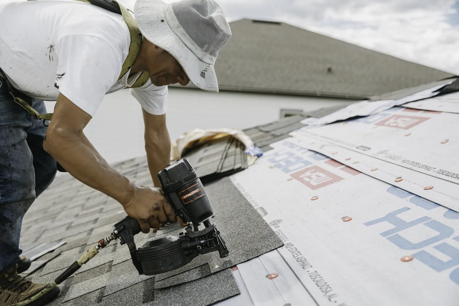 Roofer fastening starter shingles along a roof edge