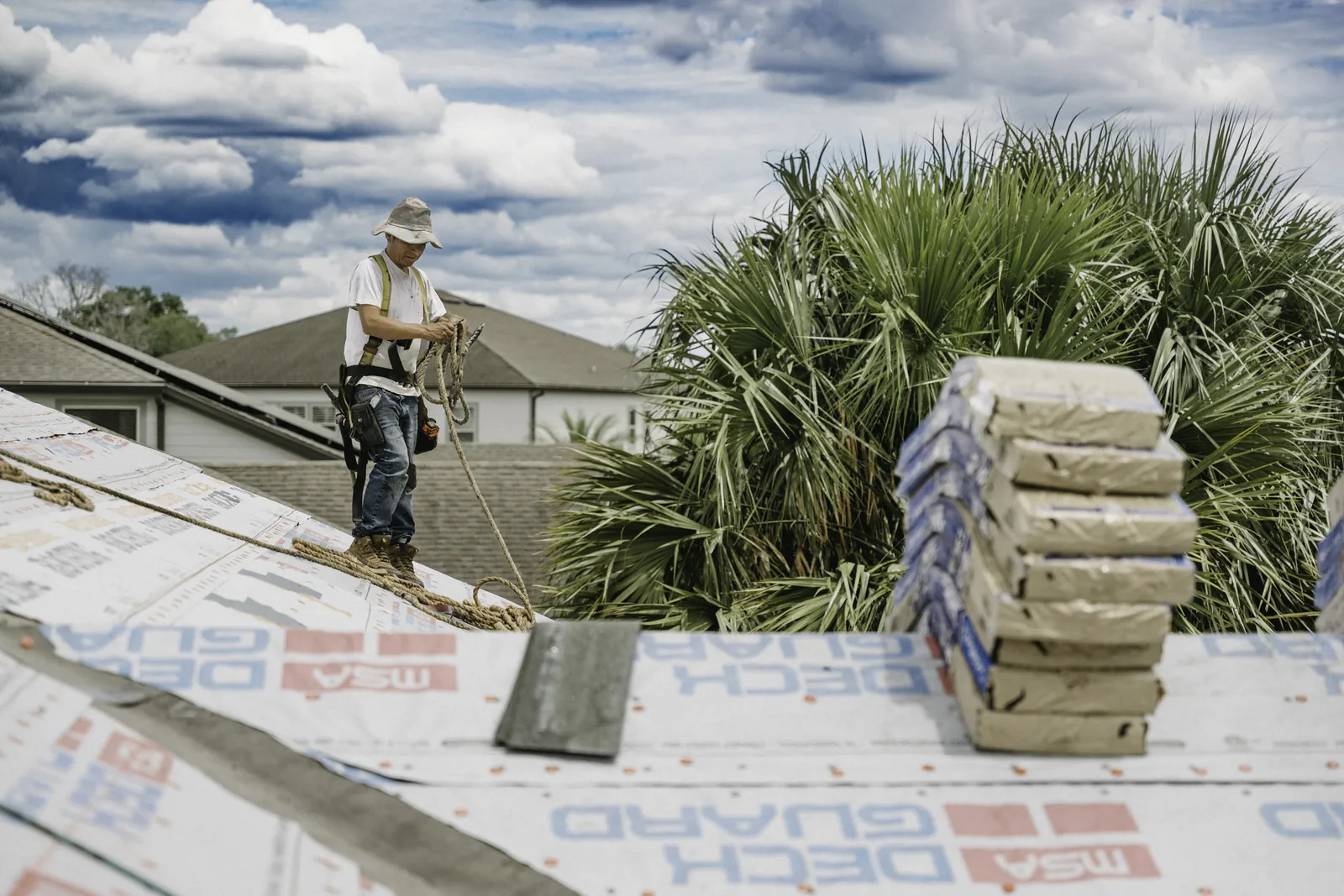 Roofer beside shingle bundles during a residential installation