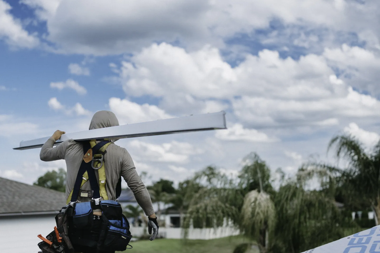 Roofers positioning metal drip edge along a roof edge