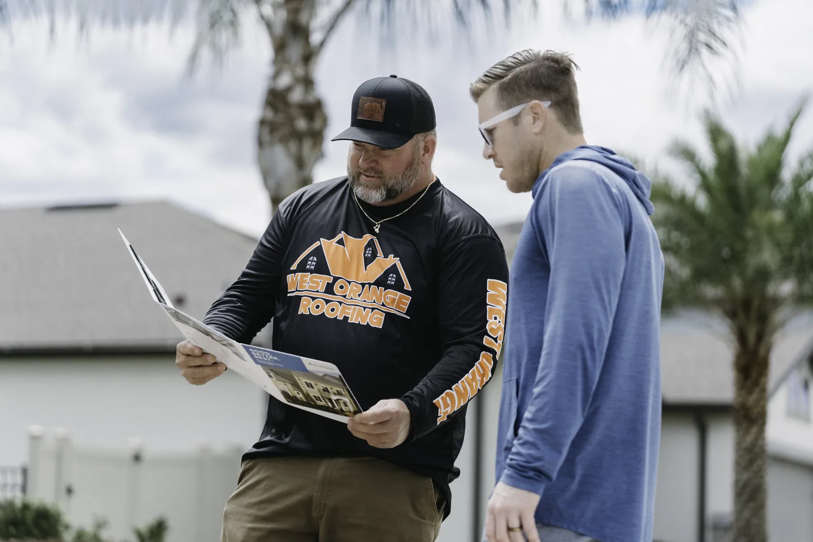 Roofing professional reviewing estimate documents with a homeowner