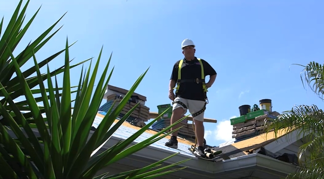 A West Orange Roofing crew member standing on a roof.