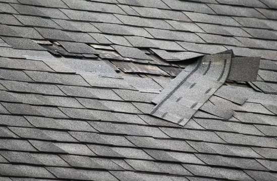 Damaged shingles ripped away from a roof