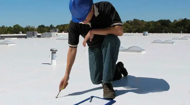 A West Orange Roofing crew member inspecting the top of a commercial roof.