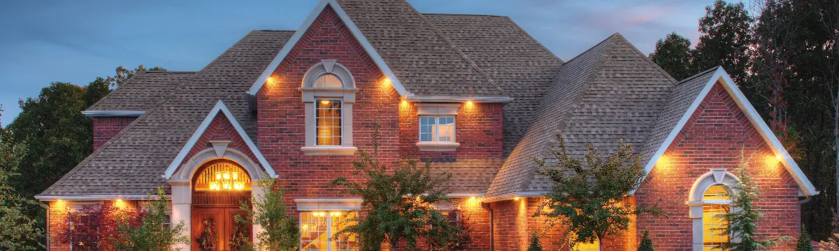A beautiful home lit up at night with a new asphalt shingle roof